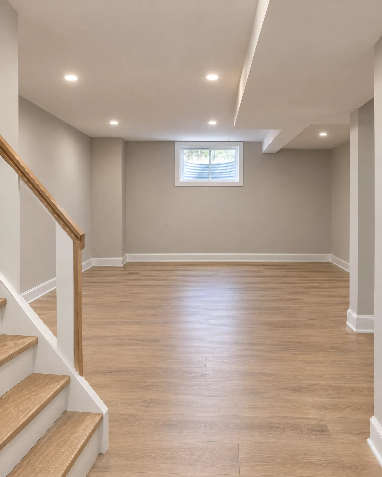 Basement from the bottom of the stairs, bare concrete before and finished family room after (after)